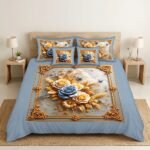 A symmetrical photograph focusing on a king bed featuring the REALFOUND D10266 bedding set. The unique light blue comforter features an intricate, ornate baroque gold frame motif enclosing a stunning central print of blue and yellow roses, butterflies, and golden wheat. Matching pillows and cushions are arranged against a wooden headboard, flanked by lit bedside lamps and furniture in a neutral bedroom.